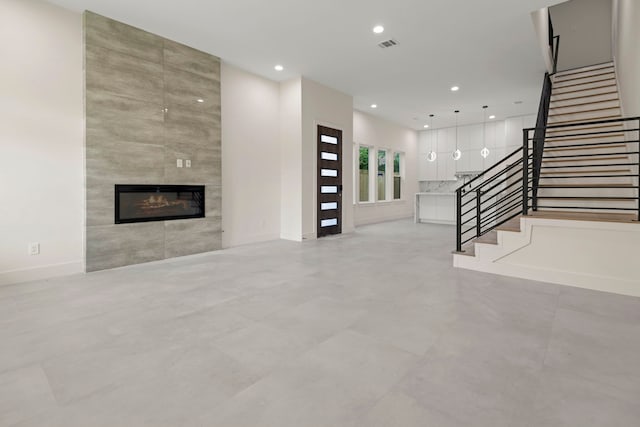 unfurnished living room featuring stairway, recessed lighting, a tile fireplace, and baseboards