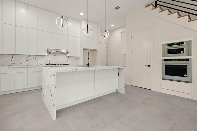 kitchen featuring visible vents, white cabinets, under cabinet range hood, and a sink