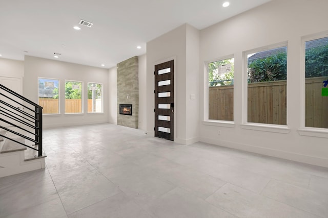 unfurnished living room with recessed lighting, a tile fireplace, light tile patterned floors, baseboards, and stairway