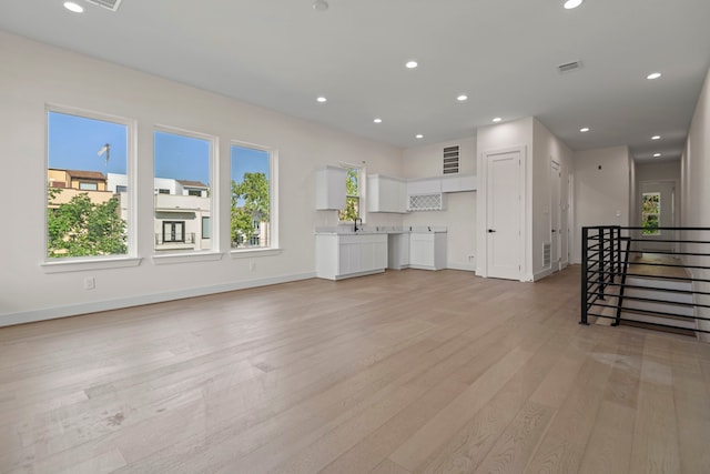 unfurnished living room with visible vents, plenty of natural light, and light wood-style floors
