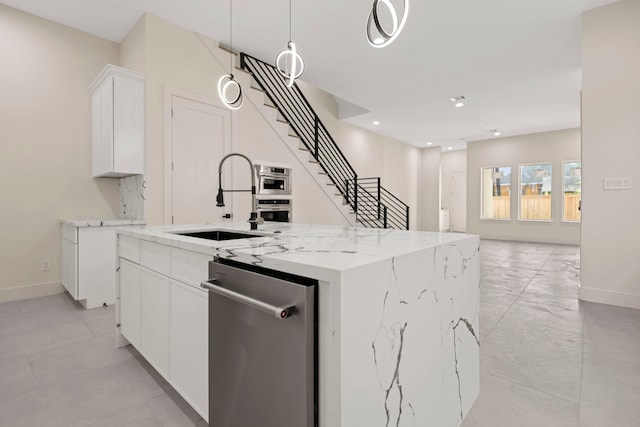kitchen with white cabinetry, a sink, stainless steel appliances, baseboards, and a center island with sink