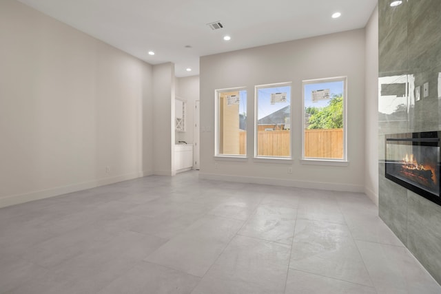 interior space with recessed lighting, a tile fireplace, visible vents, and baseboards