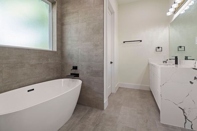 bathroom with baseboards, a freestanding bath, and vanity