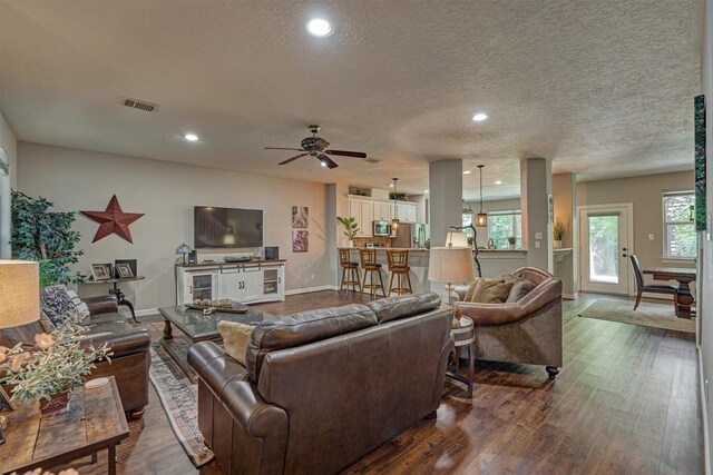living area with visible vents, ceiling fan, and dark wood-style floors