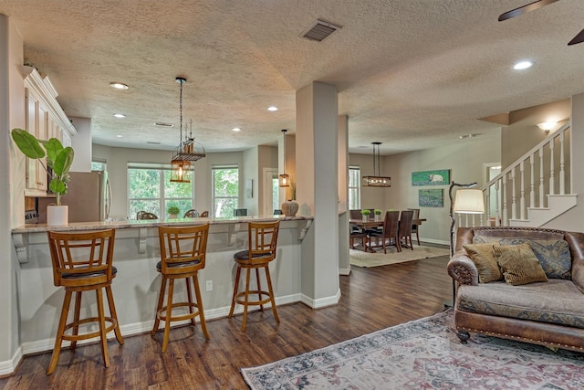 living room with baseboards, a textured ceiling, recessed lighting, and dark wood finished floors