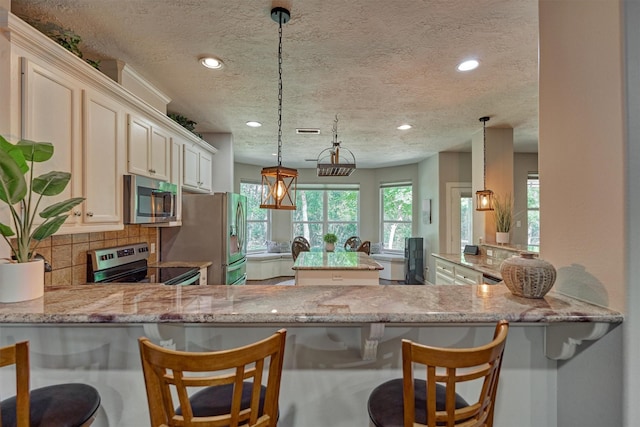 kitchen with a textured ceiling, a peninsula, and stainless steel appliances