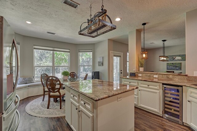 kitchen with visible vents, freestanding refrigerator, dark wood-style floors, wine cooler, and a textured ceiling