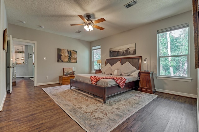bedroom featuring dark wood-style flooring, visible vents, baseboards, and a textured ceiling
