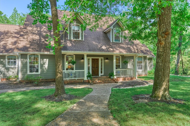 cape cod-style house featuring roof with shingles, a porch, and a front lawn
