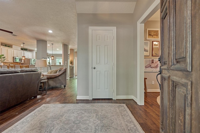 entrance foyer with a ceiling fan, a textured ceiling, baseboards, and dark wood-style floors