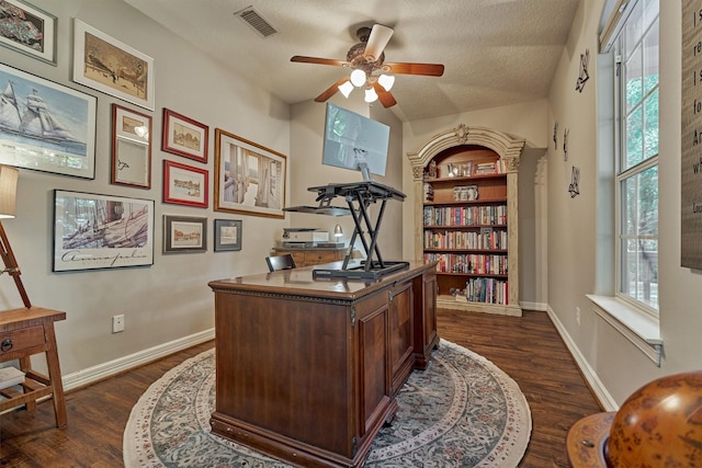 home office with ceiling fan, dark wood-type flooring, a textured ceiling, visible vents, and baseboards