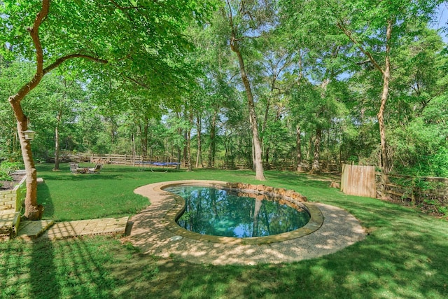 view of yard featuring a trampoline and fence