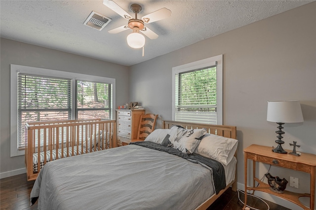 301 Chestnut Bnd, Huntsville, TX 77320 - bedroom featuring wood finished floors, visible vents, baseboards, a textured ceiling, and ceiling fan
