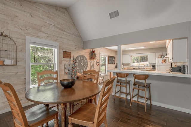301 Chestnut Bnd, Huntsville, TX 77320 - dining room featuring wood walls, a healthy amount of sunlight, lofted ceiling, dark wood-style flooring, and visible vents