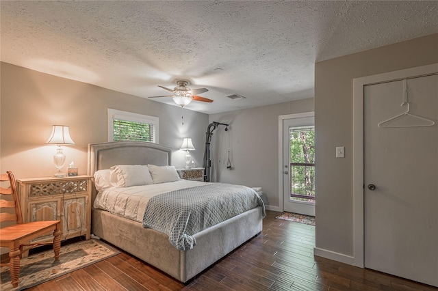 301 Chestnut Bnd, Huntsville, TX 77320 - bedroom featuring dark wood finished floors, visible vents, a textured ceiling, and ceiling fan