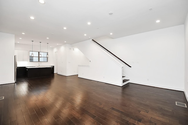 unfurnished living room featuring baseboards, recessed lighting, stairway, dark wood-type flooring, and visible vents