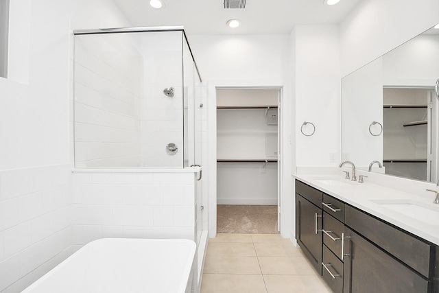 bathroom featuring a shower stall, a freestanding bath, a sink, and a spacious closet