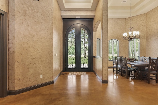 entryway with arched walkways, finished concrete flooring, french doors, and a tray ceiling