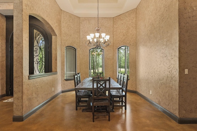 dining room featuring arched walkways, concrete flooring, an inviting chandelier, and a tray ceiling
