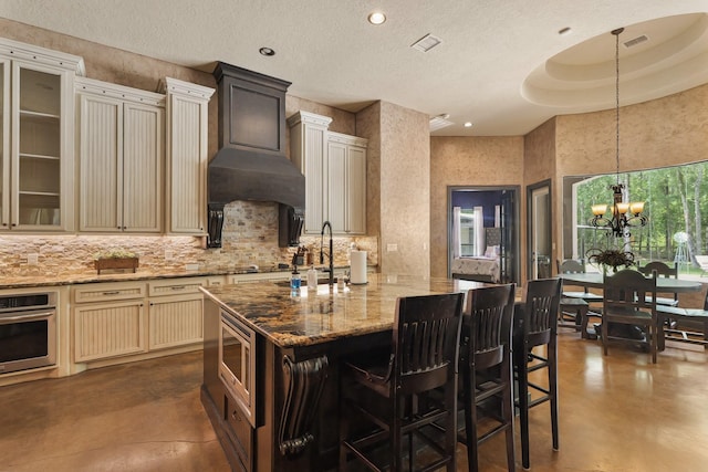 kitchen featuring appliances with stainless steel finishes, concrete floors, backsplash, a sink, and cream cabinetry