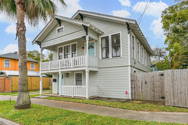 view of front of property with a porch, fence, and a balcony