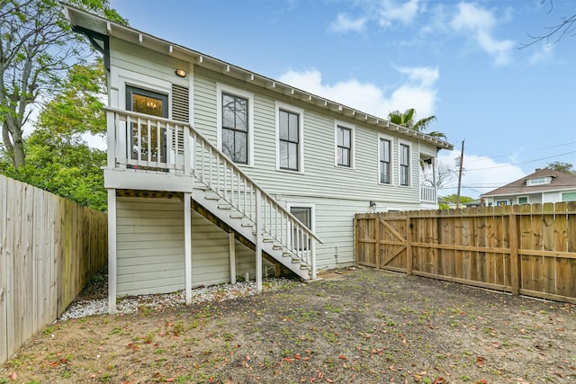 rear view of property with a fenced backyard and stairs