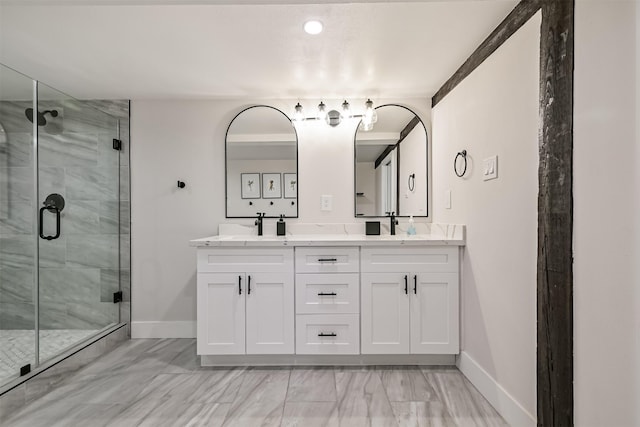 full bath featuring a stall shower, double vanity, and baseboards