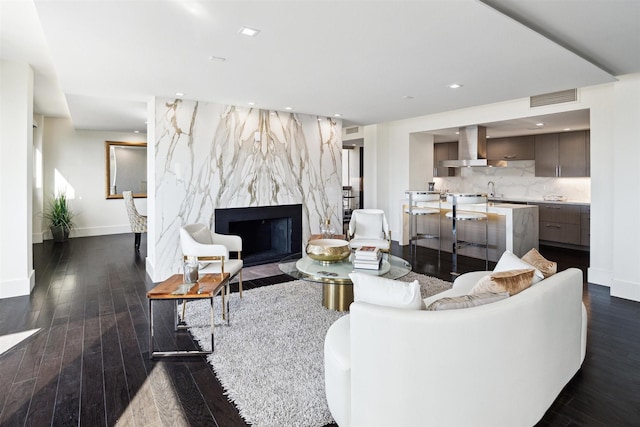 living area with a high end fireplace, baseboards, dark wood-style floors, and visible vents