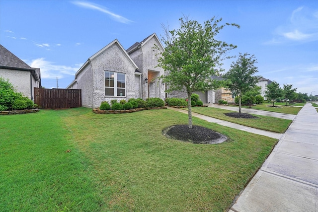 view of front facade featuring a front yard, driveway, a garage, and fence