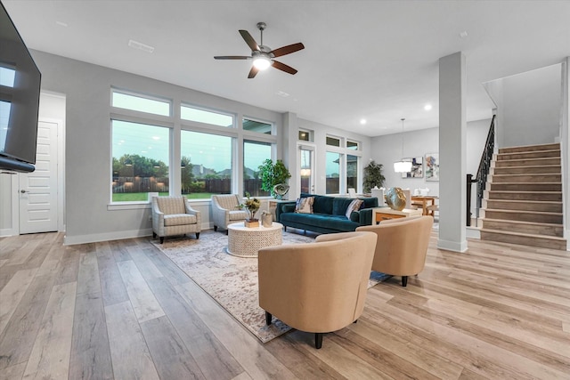 living area featuring baseboards, recessed lighting, light wood finished floors, a ceiling fan, and stairs