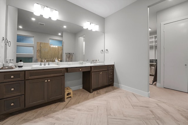 full bath with a tile shower, baseboards, visible vents, and a sink