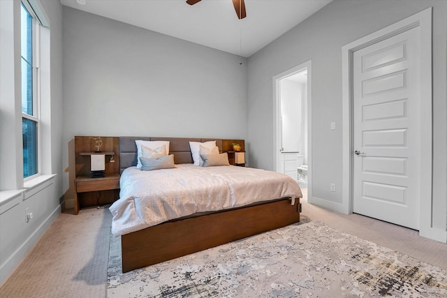 bedroom featuring baseboards, a ceiling fan, light carpet, and ensuite bath