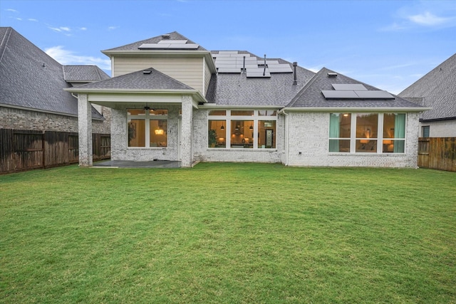 back of property featuring roof mounted solar panels, a patio, a ceiling fan, and a fenced backyard