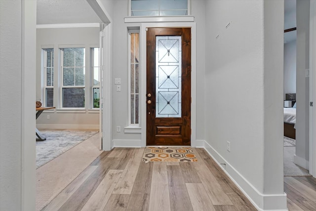 entrance foyer with baseboards, wood finished floors, and crown molding