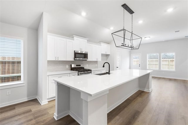 kitchen featuring a sink, appliances with stainless steel finishes, a chandelier, white cabinetry, and a spacious island