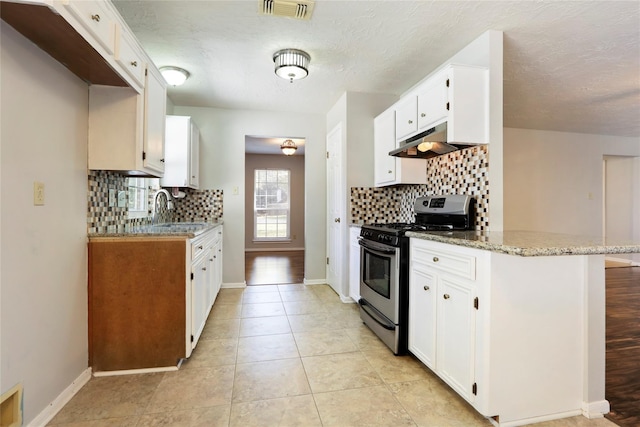 10507 Twin Oak Dr, Conroe, TX 77385 - kitchen with stainless steel gas range oven, under cabinet range hood, backsplash, a sink, and a textured ceiling