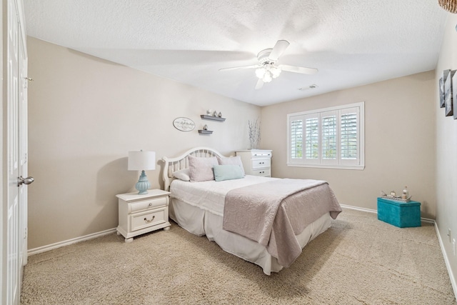 bedroom featuring visible vents, baseboards, ceiling fan, a textured ceiling, and light colored carpet