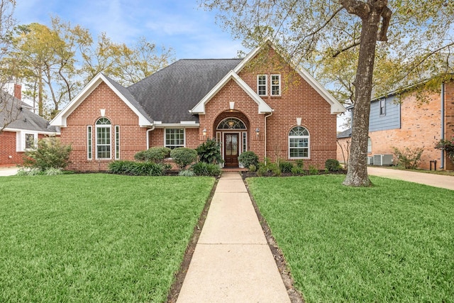 view of front of house featuring brick siding, a front yard, and roof with shingles