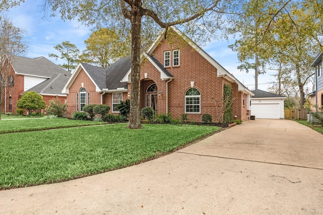 traditional-style house with a shingled roof, a garage, an outdoor structure, brick siding, and a front lawn