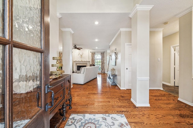 entryway featuring a fireplace, baseboards, ornamental molding, and wood finished floors
