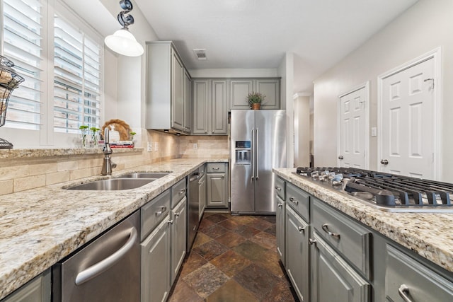 kitchen featuring visible vents, stone finish flooring, appliances with stainless steel finishes, a sink, and gray cabinetry