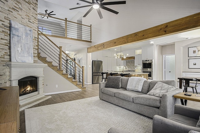 17939 Channel Hill Dr, Cypress, TX 77433 - living area with baseboards, a lit fireplace, stairway, ceiling fan with notable chandelier, and wood finished floors