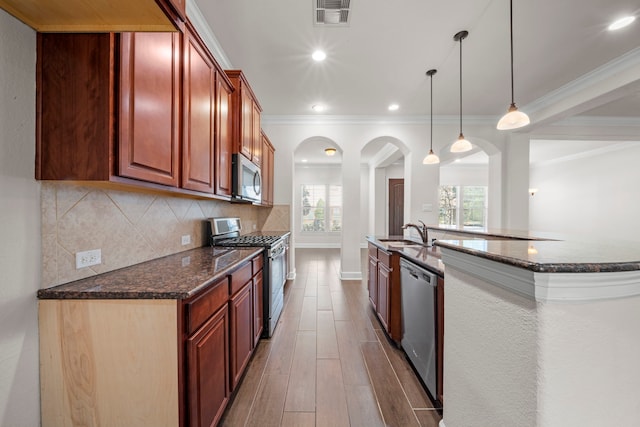 kitchen featuring visible vents, arched walkways, a sink, stainless steel appliances, and backsplash