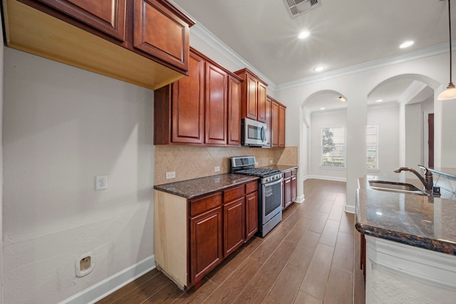 kitchen with dark stone counters, visible vents, a sink, stainless steel appliances, and backsplash