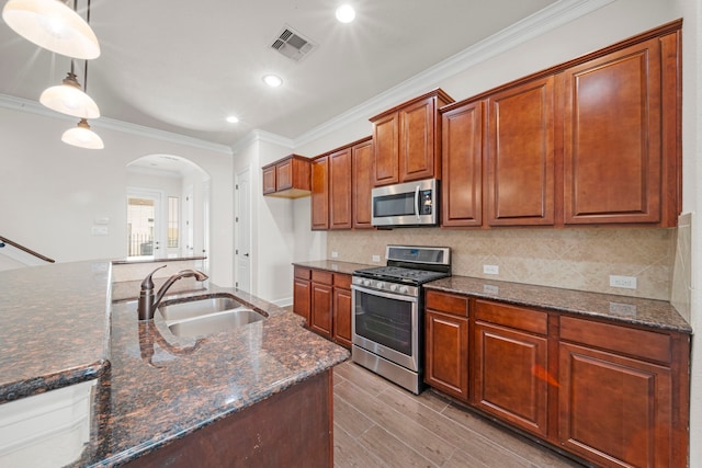 kitchen with visible vents, arched walkways, a sink, ornamental molding, and stainless steel appliances