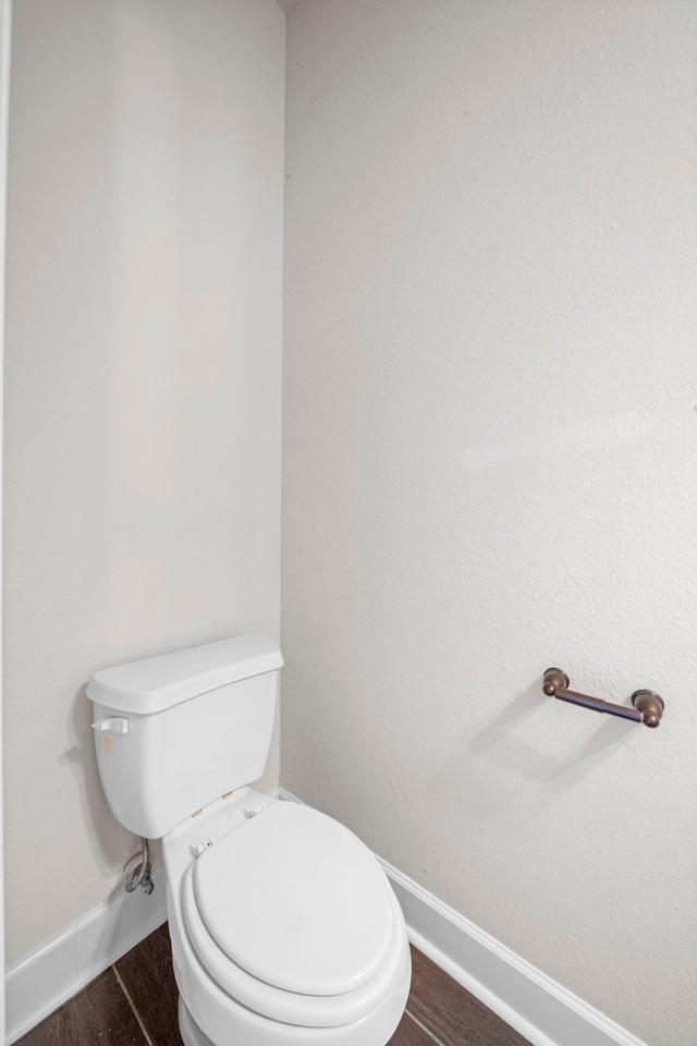 bathroom featuring baseboards, toilet, and wood finished floors