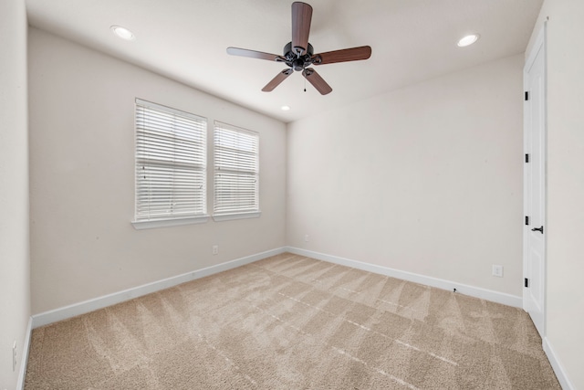 spare room with light colored carpet, ceiling fan, and baseboards