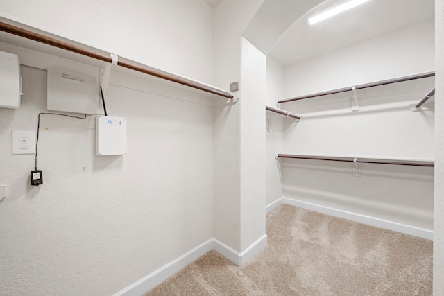 spacious closet with arched walkways and carpet flooring