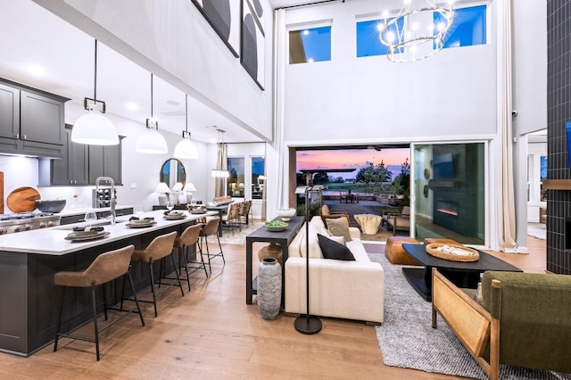 living area featuring light wood finished floors, a notable chandelier, and a towering ceiling