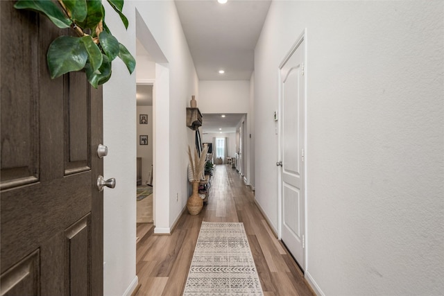 hall with baseboards, recessed lighting, and light wood-style flooring